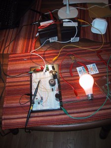 Breadboard with electronic components and wires, lighting up a lightbulb