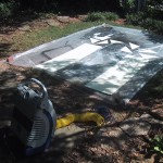 bare plywood laying on a plastic dropcloth with an air compressor and spray gun