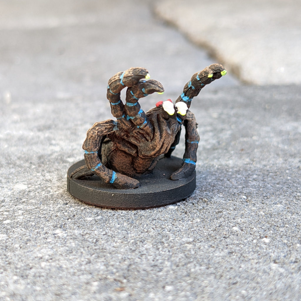 Front view showing dots of neon yellow "venom" on the fangs and tips of front legs