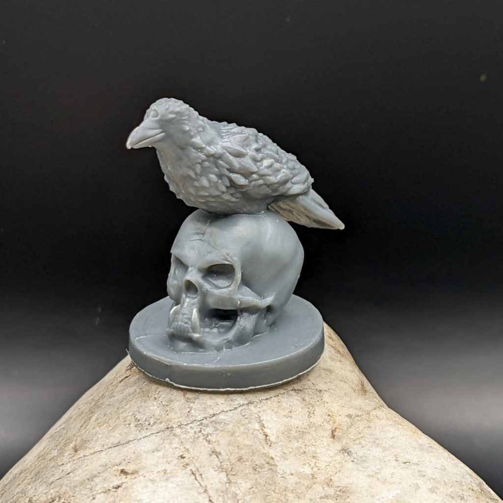 plastic raven sitting on a skull miniature, unprimed.