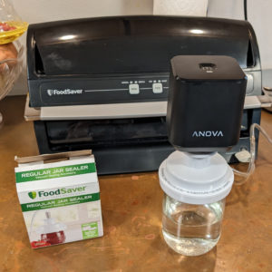 Anova handheld vacuum sealer on top of a foodsaver jar sealer