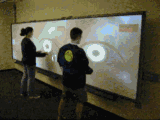 Two people playing a game on a very large projected display